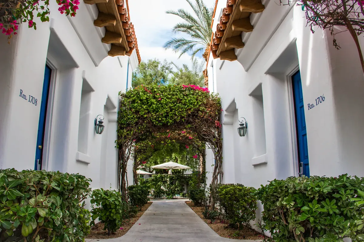 Charming resort pathway with blue doors and lush greenery in La Quinta, CA.