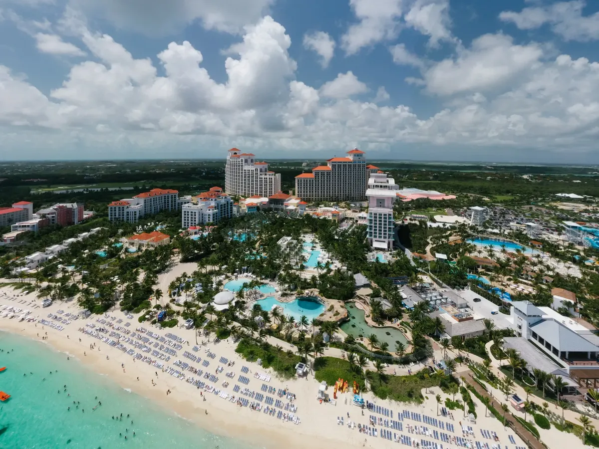 A stunning aerial shot of a luxury resort by the beach in the Bahamas, featuring pools and palm trees.