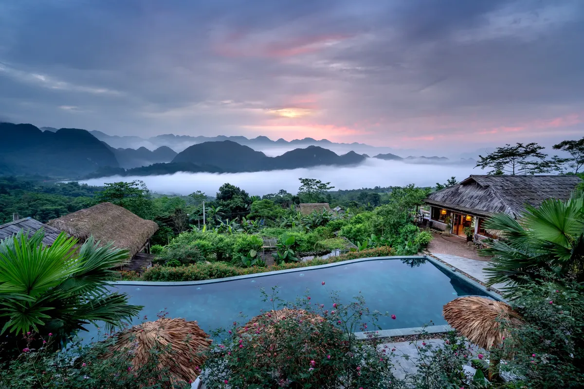 Stunning mountain resort view with pool and sunrise clouds, perfect for a peaceful getaway.